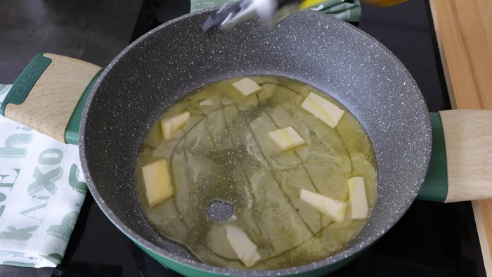 Cazo con mantequilla derritiéndose junto a un chorro de aceite
