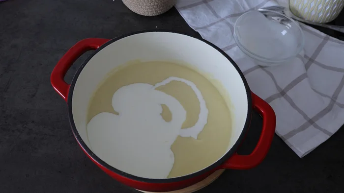 Crema blanca mezclada con nata líquida en cazuela de hierro