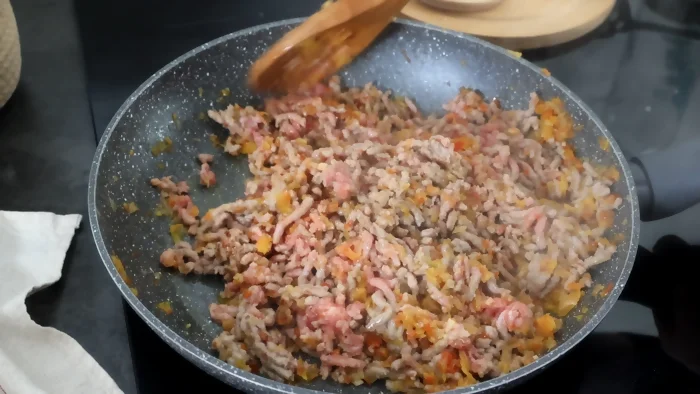  Carne picada añadiéndose a la sartén con las verduras