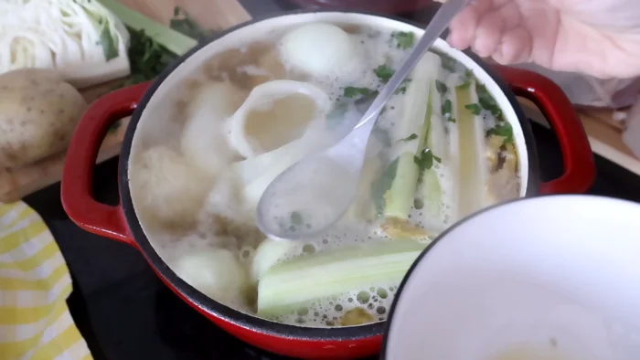 Retirando la espuma del caldo de pollo mientras hierve para obtener mejor sabor