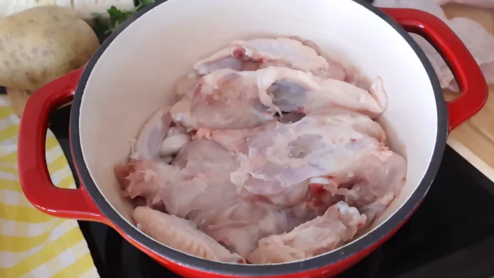 Pollo dorándose en la olla con ajo para preparar caldo