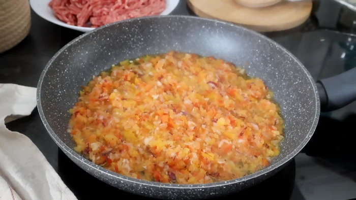 Pimientos, cebolla y ajo cocinándose en una sartén a fuego suave