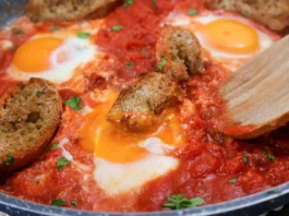 Huevos al purgatorio con tomate, huevo y pan en sartén.