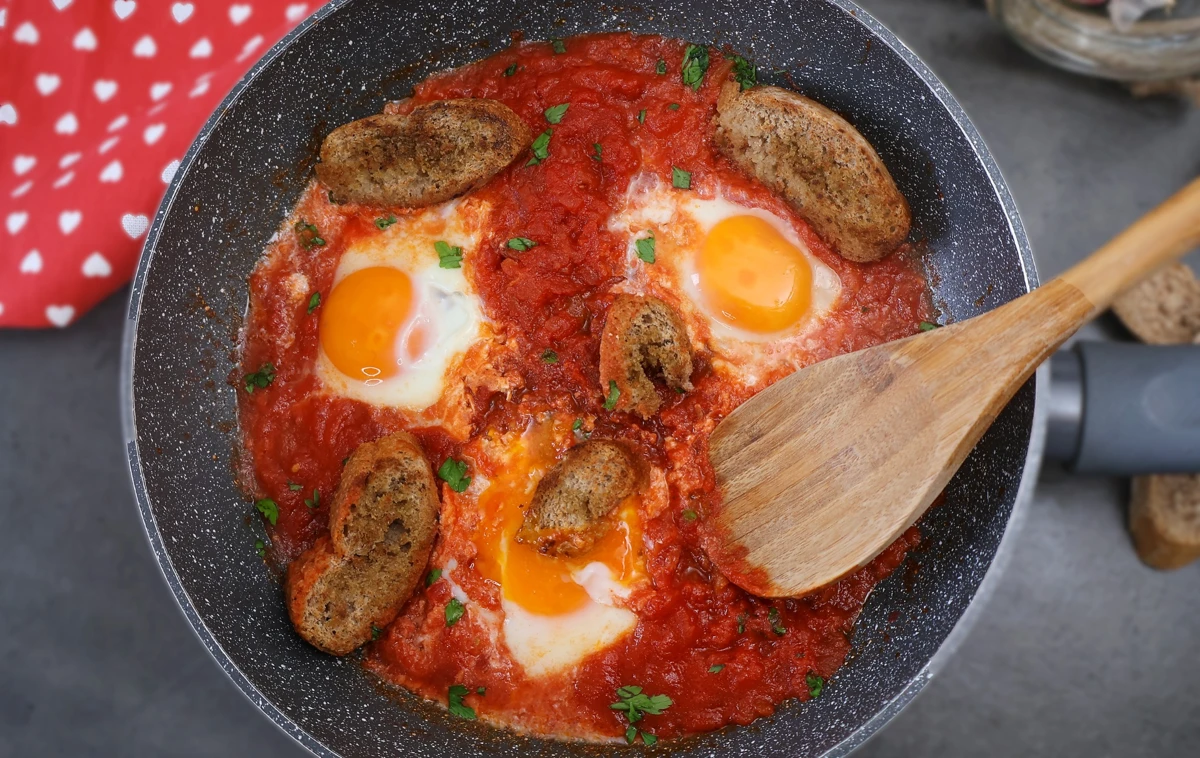 Sartén con huevos al purgatorio rodeados de pan crujiente