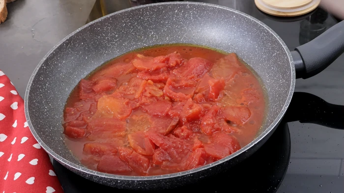 Tomates pelados cocinándose en la sartén.