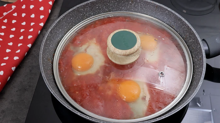 Huevos al purgatorio cocinándose con tapa.