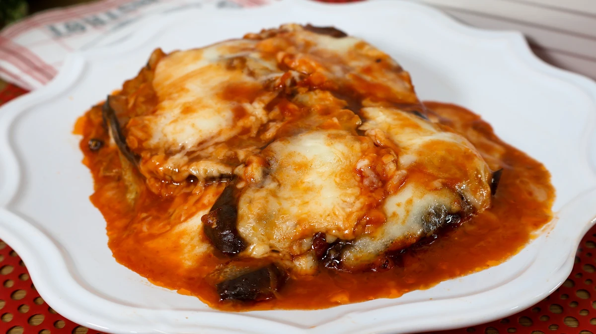 Ración servida de berenjenas a la parmesana fundida y jugosa en el plato