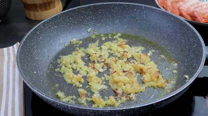  Sofrito de cebolla, ajo y azafrán en sartén para base de salsa