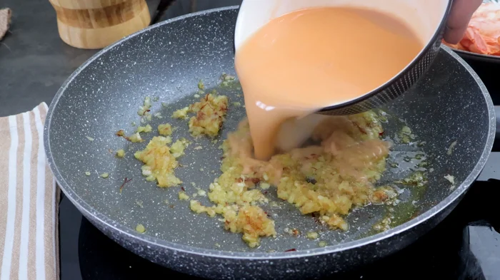 Fumet de gambas vertido en sartén sobre sofrito