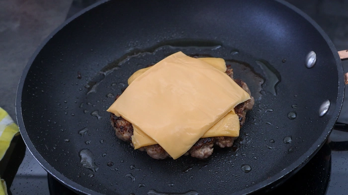 Hamburguesa cocinada con lonchas de queso cheddar fundiéndose