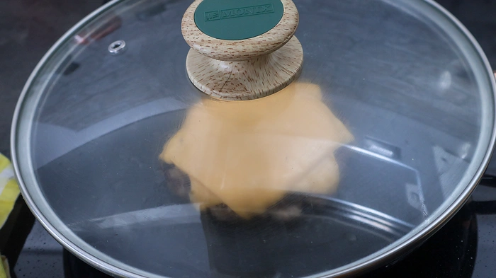 Hamburguesa tapada con queso cheddar fundiéndose al vapor