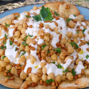 Fatteh de garbanzos con yogur y piñones sobre pan de pita crujiente
