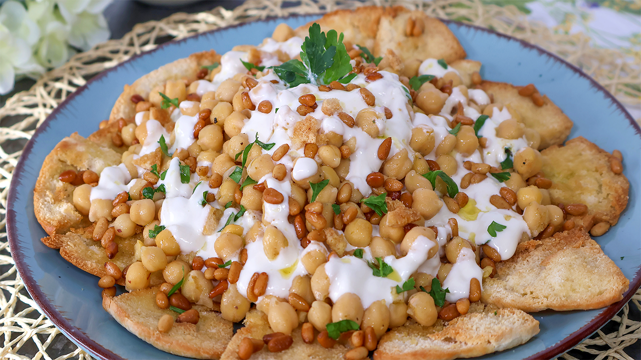 Fatteh de garbanzos con yogur y piñones sobre pan de pita crujiente