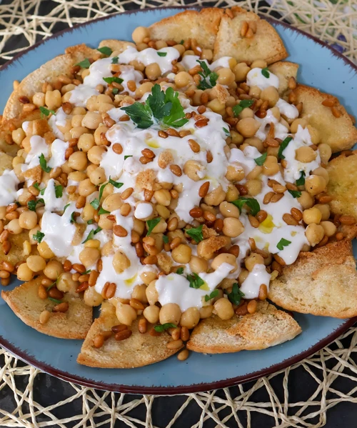 Fatteh con garbanzos, yogur y piñones sobre pan crujiente