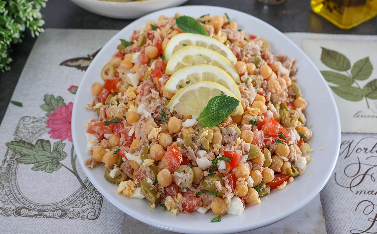 Fuente ovalada con ensalada de garbanzos decorada con rodajas de limón