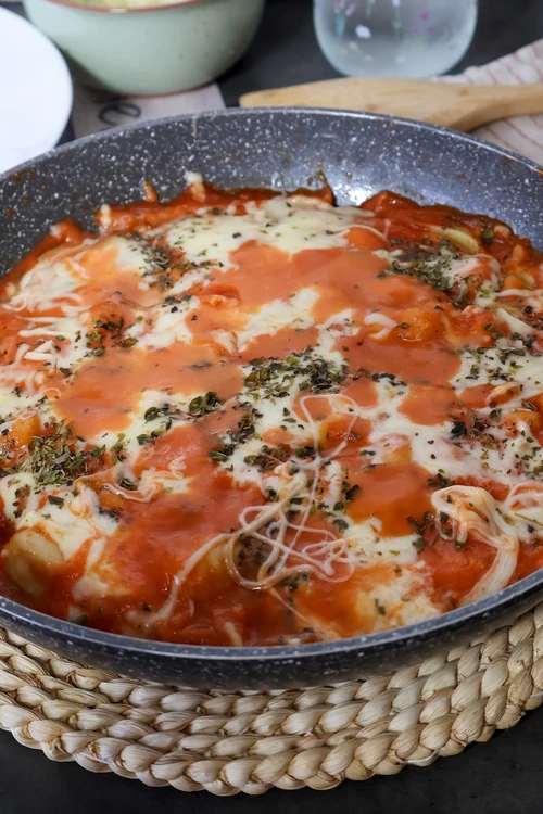 Detalle de ñoquis fundentes con tomate y queso estirado