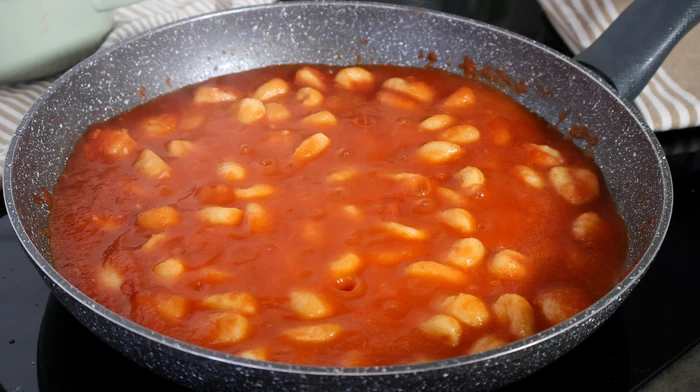 Ñoquis cocinándose en salsa de tomate casera