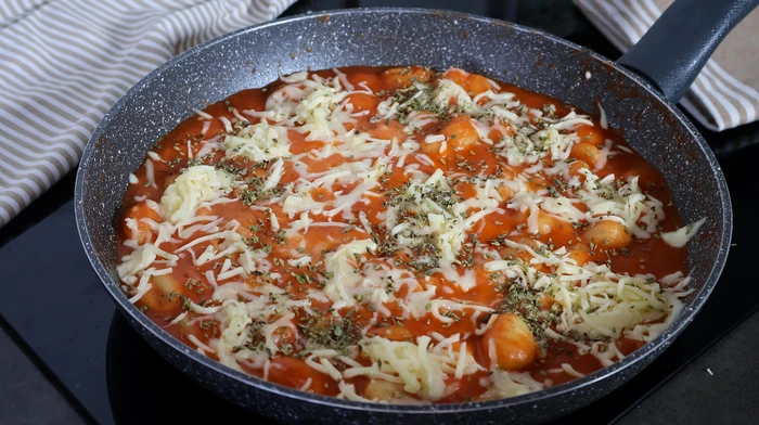 Ñoquis en sartén con queso rallado y orégano antes de servir