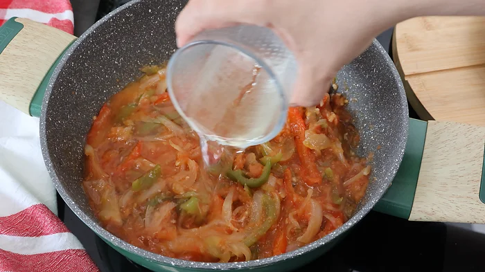 Mano vertiendo vino blanco en el sofrito con verduras