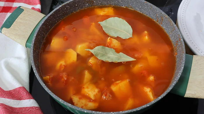 Cazuela con patatas y caldo de pescado al fuego con laurel