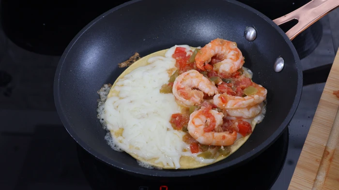 Tortilla con queso fundente y relleno de camarones en sartén