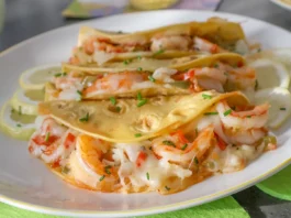 Tacos Gobernador rellenos de camarones, queso fundido y sofrito, servidos en plato blanco con rodajas de limón