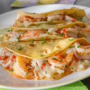 Tacos Gobernador rellenos de camarones, queso fundido y sofrito, servidos en plato blanco con rodajas de limón