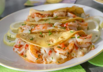 Tacos Gobernador rellenos de camarones, queso fundido y sofrito, servidos en plato blanco con rodajas de limón