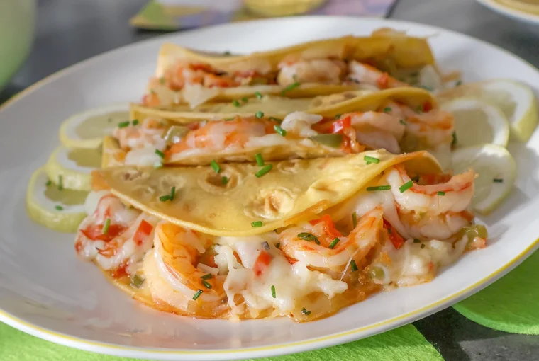 Tacos Gobernador rellenos de camarones, queso fundido y sofrito, servidos en plato blanco con rodajas de limón