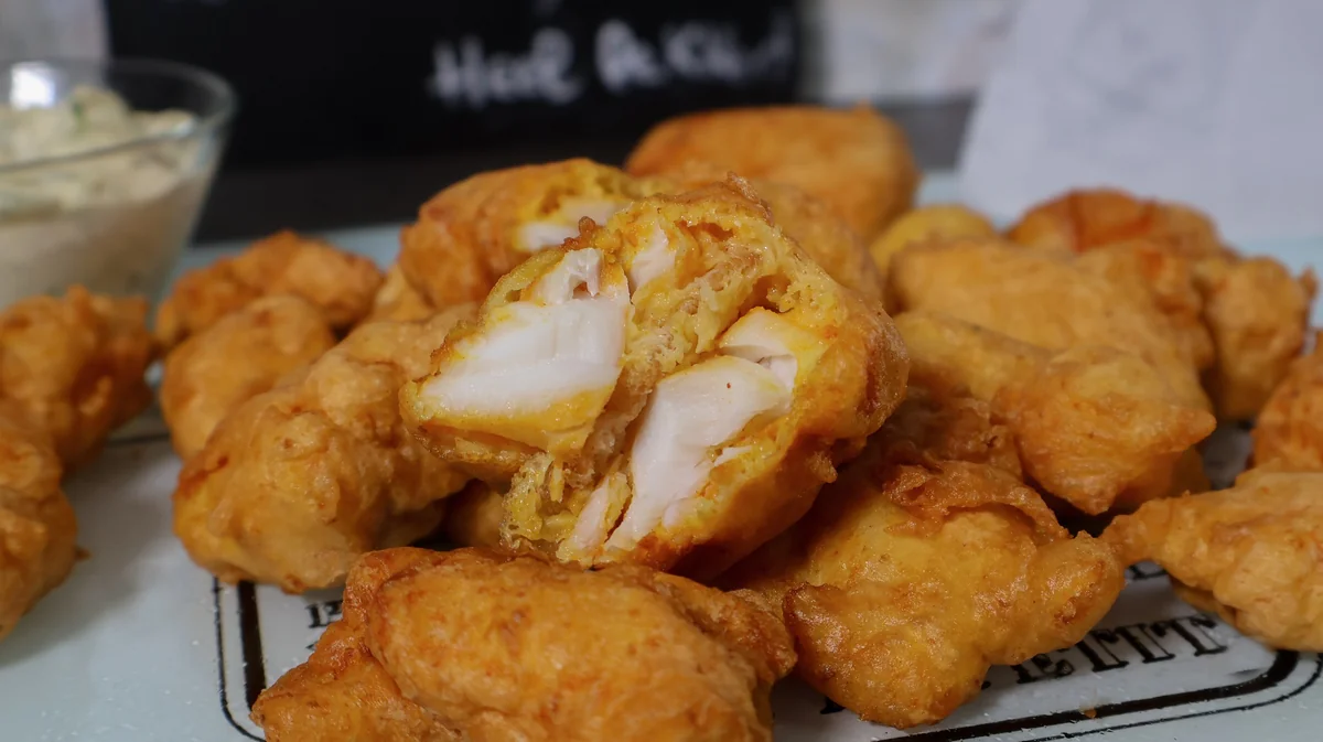 Interior del kibbeling mostrando bacalao blanco y jugoso bajo el rebozado crujiente.