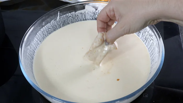 Sumergiendo un trozo de bacalao en el batido antes de freír kibbeling.