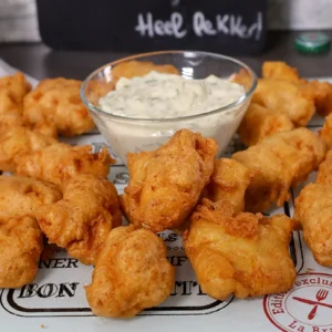 Piezas de bacalao rebozadas y fritas al estilo holandés, servidas con salsa
