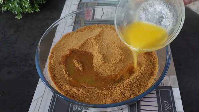 Mezclando galletas trituradas con mantequilla para la base de la tarta sin horno