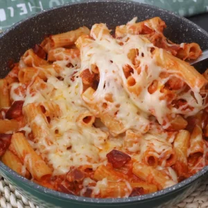 Macarrones con chorizo caseros con salsa de tomate y queso fundido en sartén