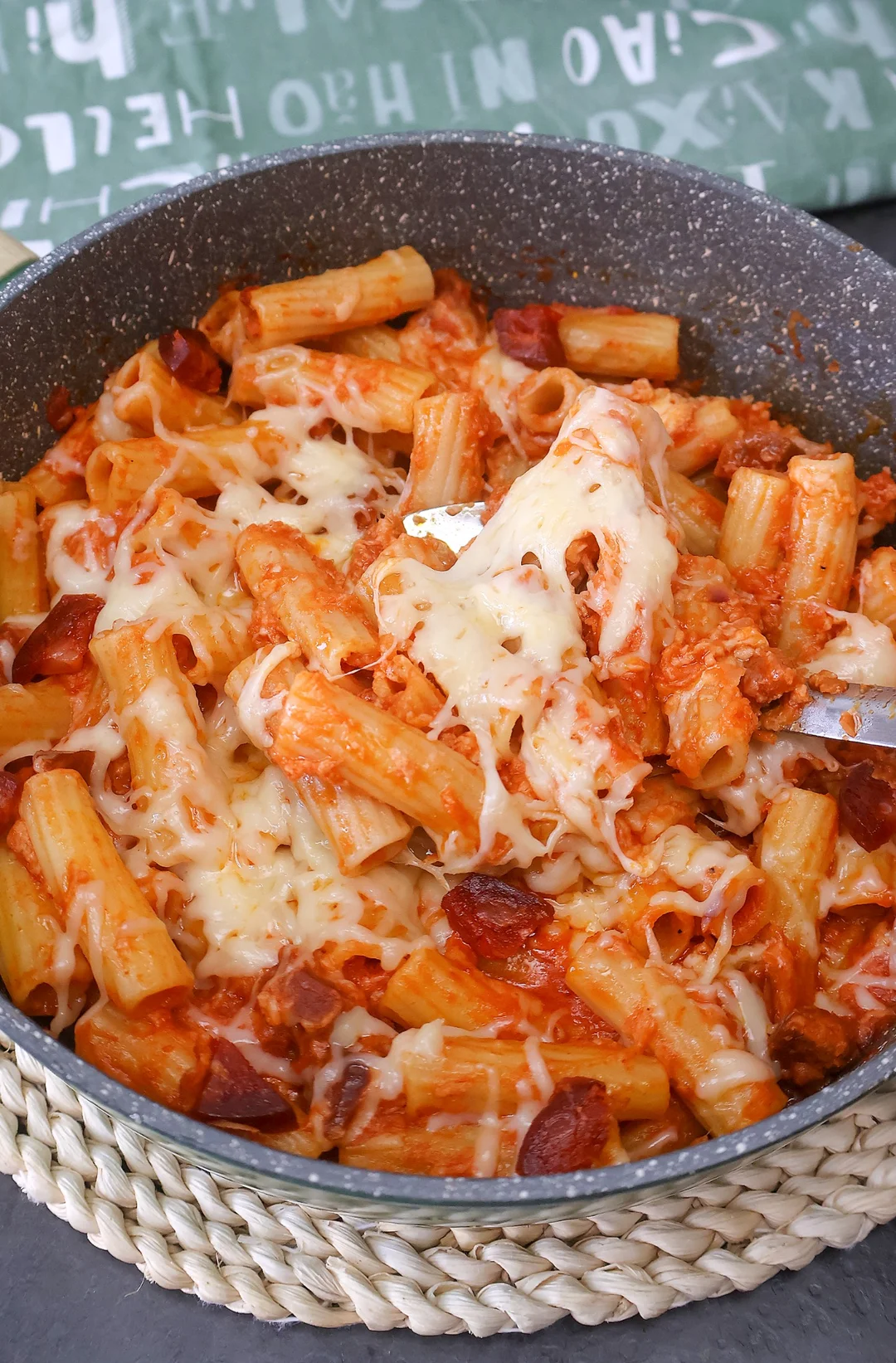 Macarrones con chorizo caseros en sartén, mezclados con salsa de tomate y queso fundido