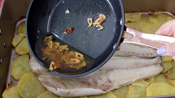 Salsa de ajos dorados y aceite vertida sobre la lubina al horno