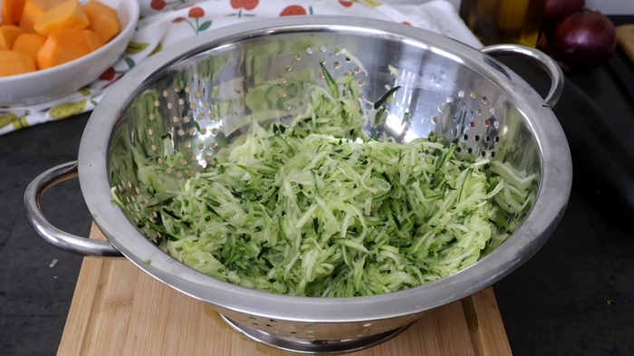 calabacín rallado escurriendo en colador para gratinado de verduras