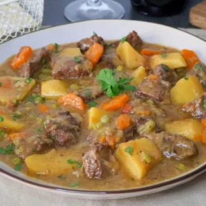 Carne guisada con patatas y verduras en plato hondo, receta tradicional casera