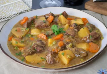 Carne guisada con patatas y verduras en plato hondo, receta tradicional casera