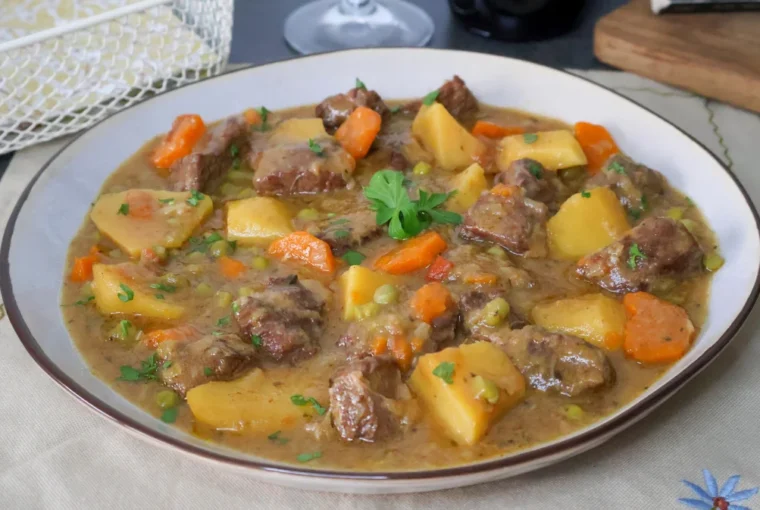 Carne guisada con patatas y verduras en plato hondo, receta tradicional casera