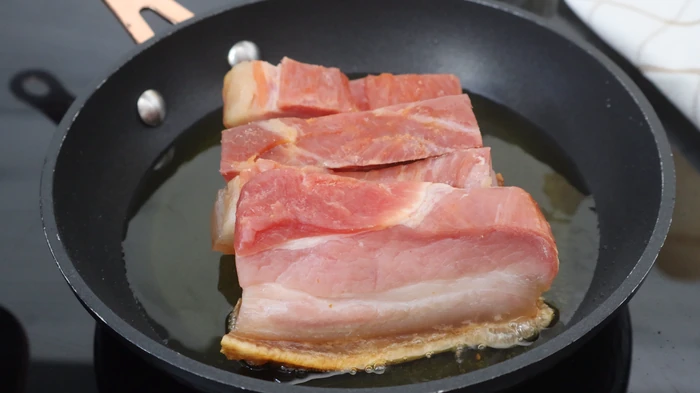 Panceta o torreznos en sartén comenzando a dorarse en su grasa