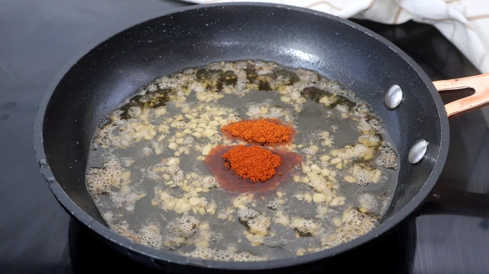Sofrito de ajos y pimentón en aceite caliente para las patatas meneás
