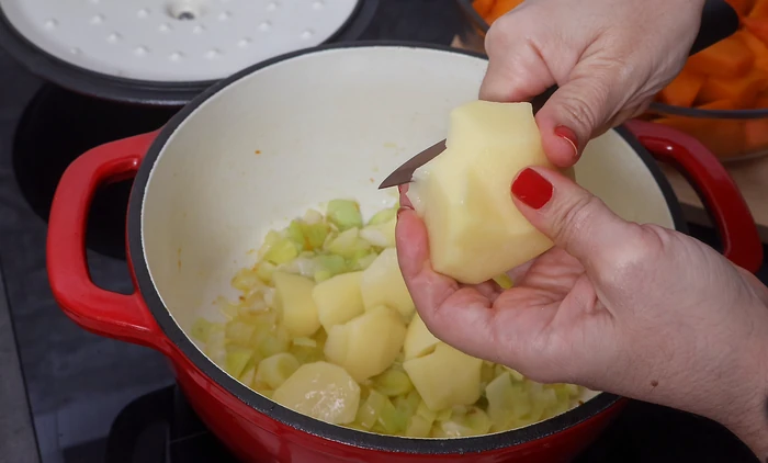Añadiendo patata troceada al sofrito de puerro para la crema de calabaza