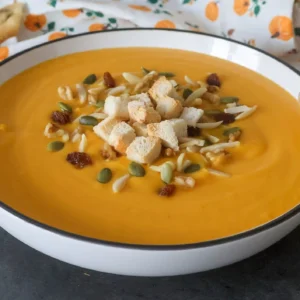 crema de calabaza y zanahoria, servida con picatostes, semillas y frutos secos