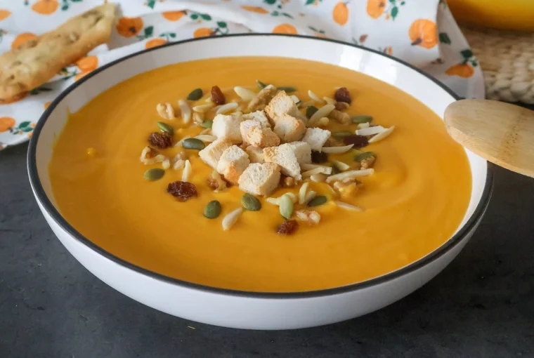 crema de calabaza y zanahoria, servida con picatostes, semillas y frutos secos