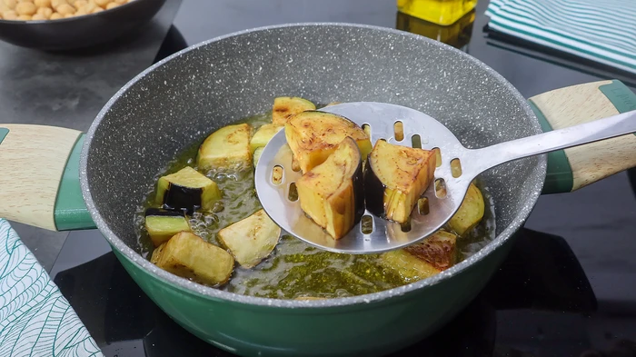 Berenjenas doradas friéndose en aceite de oliva para maghmour libanés
