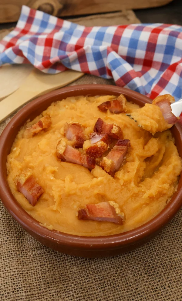 Patatas meneás tradicionales con torreznos crujientes en cazuela de barro