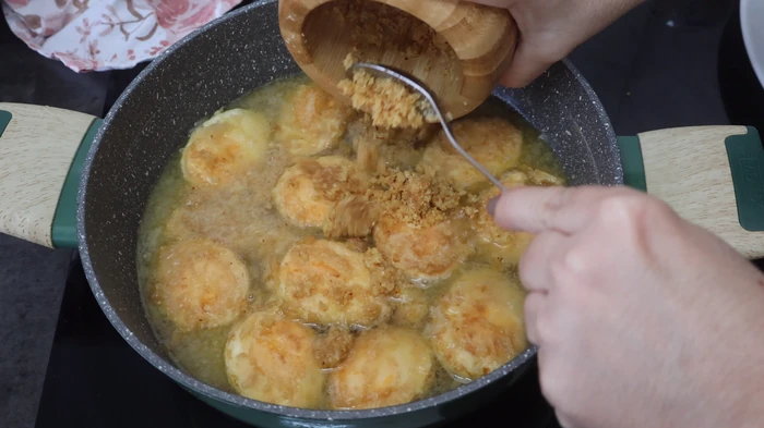 huevos rebozados guisándose en cazuela con salsa y majado