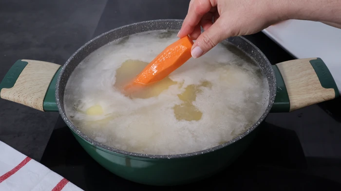 cocción de patatas y zanahorias en el caldo para el pastel de merluza