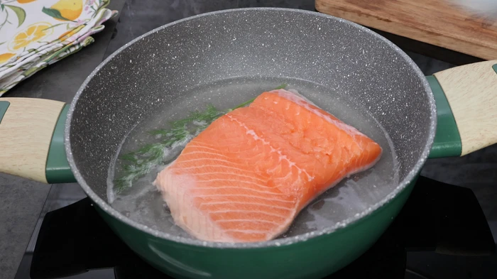 Lomo de salmón fresco cociéndose en agua con vino y eneldo